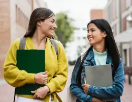 two women holding notebooks and walking outside