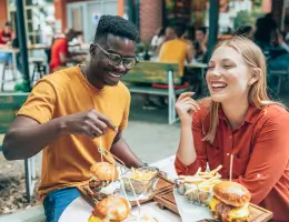 a man and a woman eating food outside of a restaurant