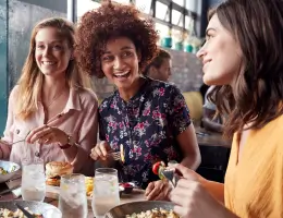 three women laugh and smile inside a restaurant
